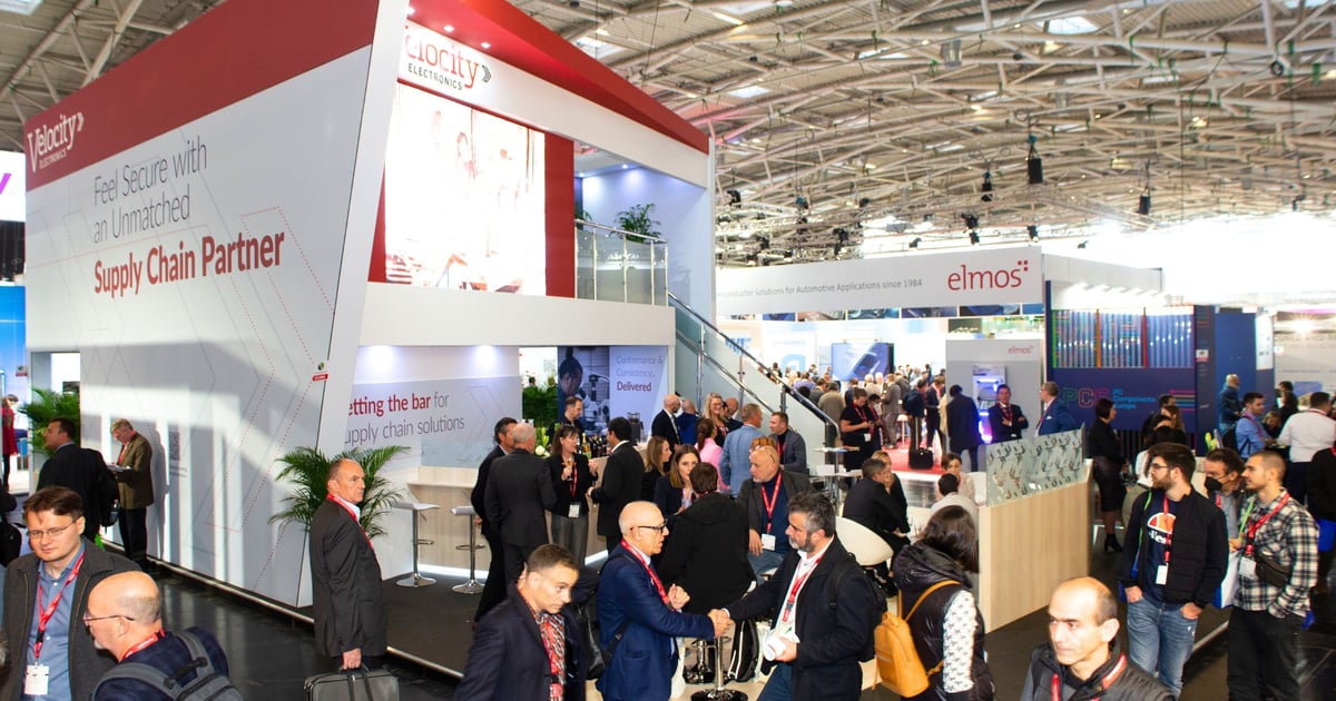 Overview image of the vibrant and engaging Velocity Electronics trade show booth at the event day, capturing attendees actively interacting, discussing, and exploring within the booth, demonstrating the booth's successful design in fostering conversation and engagement.